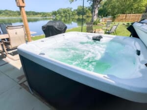 Scenic lakeside yard with hot tub and grill, offering stunning water views and relaxing outdoor amenities.