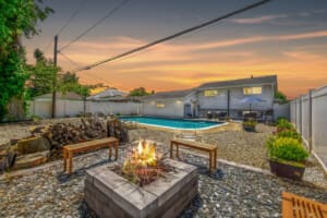Backyard oasis with a sparkling pool and modern outdoor fireplace, perfect for relaxing and entertaining.