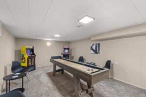 Game room in Northeast Ohio vacation rental with shuffleboard table and arcade games, perfect for guest entertainment
