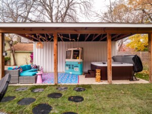 Resort-style short-term rental backyard with hot tub, fire pit seating, VW bus mini bar, string lights, and outdoor entertainment space