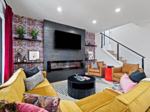 Modern short-term rental living room with accent wall design, fireplace, large flat-screen TV, and spacious seating area for guests