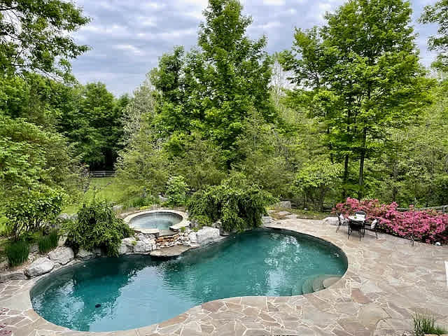 Luxury short-term rental backyard with inground pool and connected spa hot tub