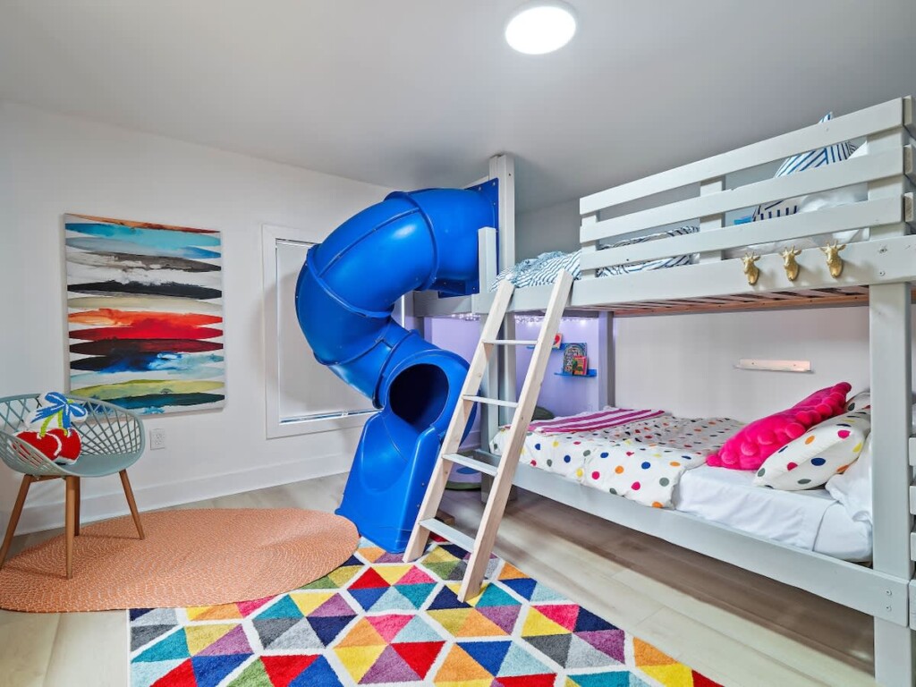 Bunk bed with a slide from the top bunk to the floor in a kids playroom at a family vacation rental