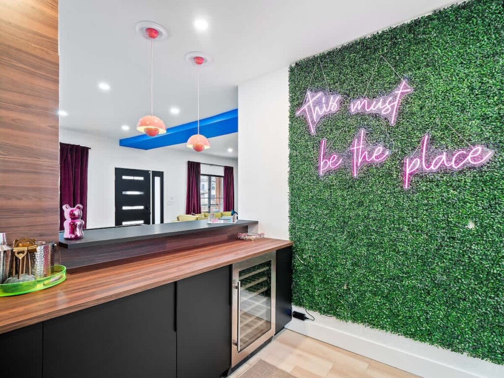 Modern open-concept kitchen and living area in a Great Lakes vacation rental, with a green accent wall and neon lighting