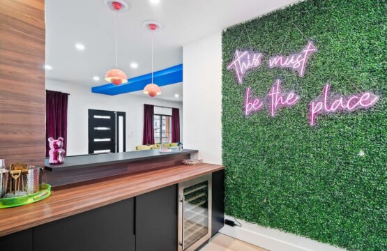 Modern open-concept kitchen and living area in a Great Lakes vacation rental, with a green accent wall and neon lighting