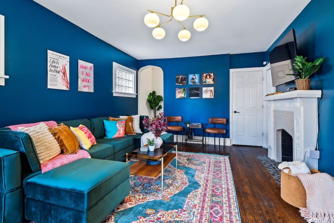 Modern vacation rental living room with colorful pillows, blue accent walls, and inviting seating for guests