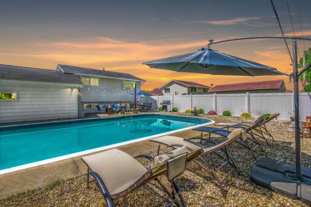 Vacation rental backyard with inground pool, fire pit, and colorful sunset sky for a relaxing Midwest getaway